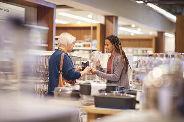 Female worker helping senior woman shopping in home goods store - CAIF27445