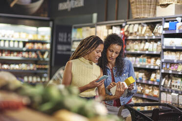 Frauen mit Smartphone beim Lebensmitteleinkauf im Supermarkt - CAIF27462