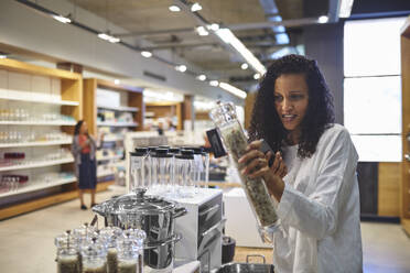 Woman shopping for pepper grinder in home goods store - CAIF27479