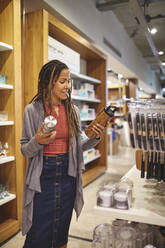 Woman shopping for insulated drink containers in home goods store - CAIF27482