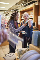 Women with smart phone shopping in home goods store - CAIF27493