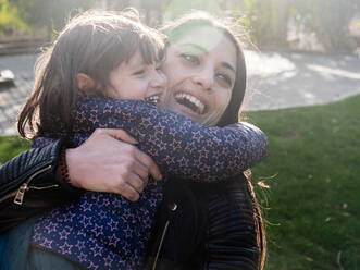 Portrait of happy little girl hugging her mother outdoors - EGAF00051