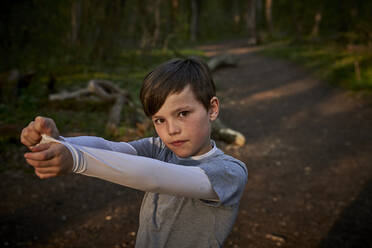 Portrait of boy pulling sleeve while standing in forest - AUF00367