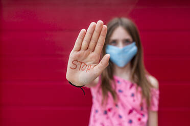Girl with face mask showing palm of her hand, saying stop - SARF04559