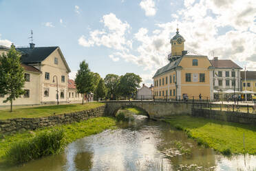 Schweden, Ostergotland, Soderkoping, Bogenbrücke über kleinen Stadtkanal mit Rathaus im Hintergrund - TAMF02211