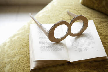 Cardboard glasses and book on lounge chair - AUF00406