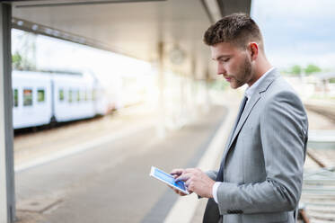 Young businessman using tablet at the train station - DIGF10444