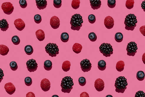 Pattern of raspberries, blueberries and blackberries against pink background - GEMF03695