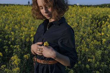 Portrait of teenage girl standing in rape field - OGF00394