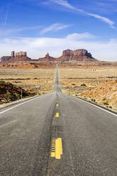 Leere Wüstenstraße in Richtung einer berühmten Felsformation gegen den Himmel, Monument Valley Tribal Park, Utah, USA - DGOF00977