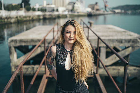 Portrait of beautiful young woman standing on pier during sunny day - MTBF00388