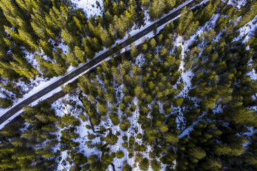 Deutschland, Bayern, Ramsau bei Berchtesgaden, Blick aus dem Hubschrauber auf eine leere Autobahn, die durch einen schneebedeckten Bergwald führt - AMF08079