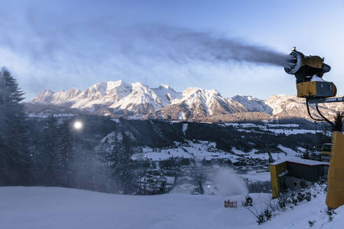 Österreich, Steiermark, Schladming, Schneekanone sprüht in der Abenddämmerung Schnee über die Planai-Piste - WFF00428