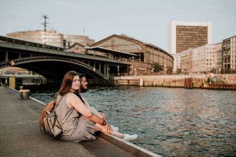 Young couple sitting at River Spree, Berlin, Germany stock photo