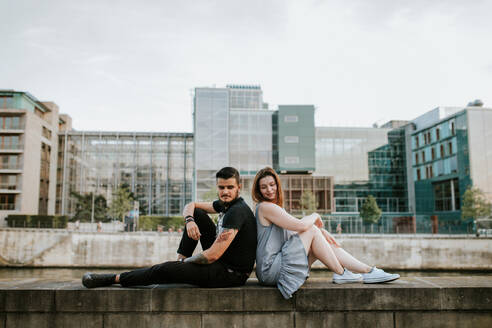 Junges Paar sitzt auf einer Mauer am Flussufer, Berlin, Deutschland - VBF00022