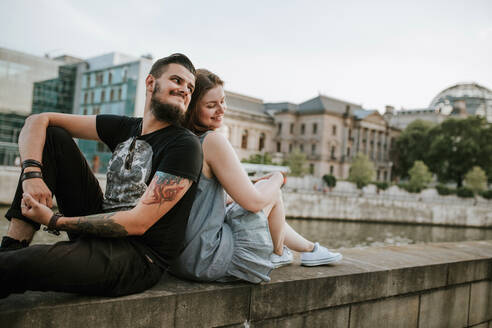 Junges Paar sitzt auf einer Mauer am Flussufer, Berlin, Deutschland - VBF00023