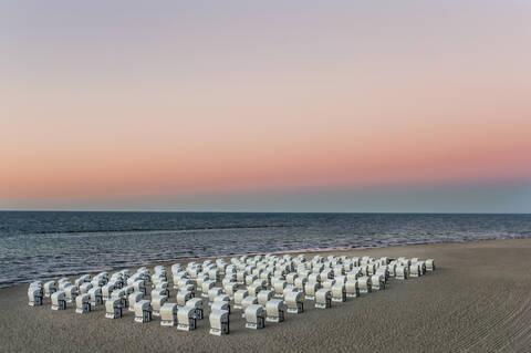 Hooded chairs at beach against sky during sunset, Ruegen, Germany stock photo