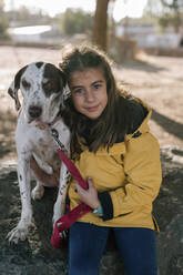 Cute girl hugging dog while sitting on rock - GRCF00201