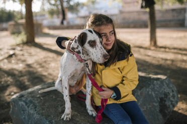 Cute girl hugging dog while sitting on rock - GRCF00202