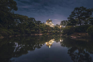 Japan, Osaka, Chuo-ku, Osaka Castle spiegelt sich im glänzenden Burggraben bei Nacht - DVGF00089