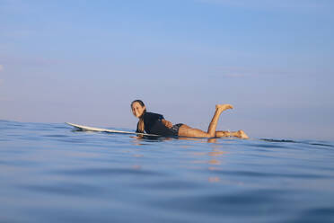 Happy woman lying on surfboard in the sea, Bali, Indonesia - KNTF04589