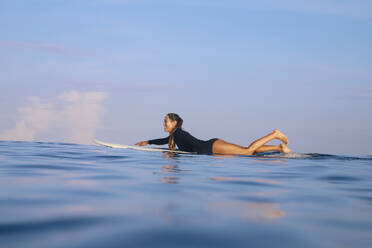 Glückliche Frau auf einem Surfbrett im Meer liegend, Bali, Indonesien - KNTF04590