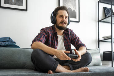Man sitting on couch and playing video game - VPIF02411