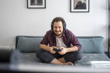 Man sitting on couch and playing video game - VPIF02416