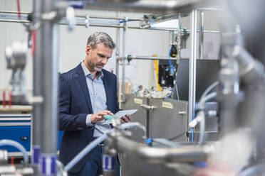 Mature businessman using tablet in a factory - DIGF10487