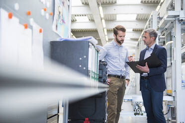 Two businessmen with folder talking in a factory - DIGF10490