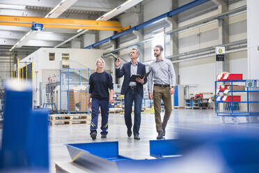 Two men and a woman walking in a factory - DIGF10498