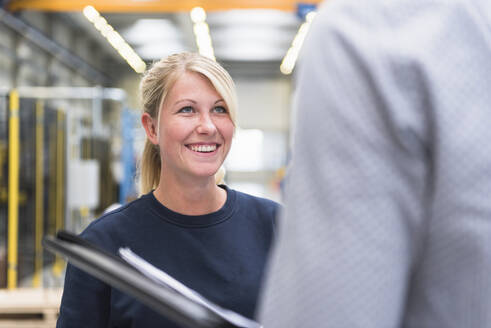 Lächelnde Frau sieht Mann in einer Fabrik an - DIGF10502