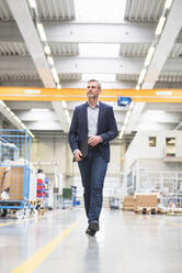 Mature businessman walking in a factory - DIGF10504