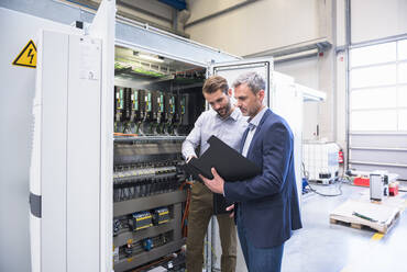 Two businessmen at a circuitry in a factory - DIGF10513