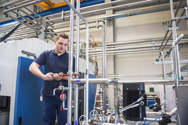 Handwerker bei der Arbeit an Rohrleitungen in einer Fabrik - DIGF10517