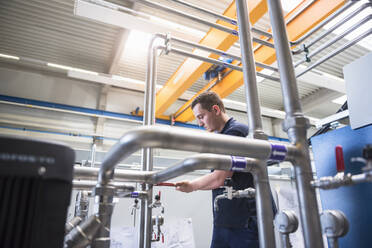 Handwerker bei der Arbeit an Rohrleitungen in einer Fabrik - DIGF10518