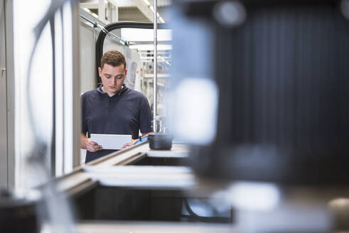 Junger Mann benutzt Tablet in einer Fabrik - DIGF10522