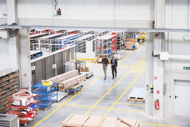 Two businessmen walking on factory shop floor - DIGF10527