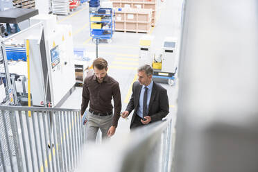 Zwei Geschäftsleute gehen eine Treppe in einer Fabrik hinauf - DIGF10533