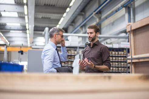 Zwei Geschäftsleute unterhalten sich in einer Fabrik - DIGF10565