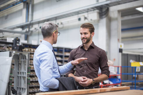 Zwei Geschäftsleute unterhalten sich in einer Fabrik - DIGF10567