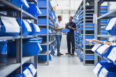 Two men talking in storehouse of a factory - DIGF10582