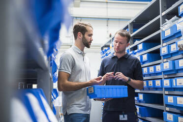 Two men talking in storehouse of a factory - DIGF10583