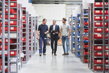 Three men talking in storehouse of a factory - DIGF10584