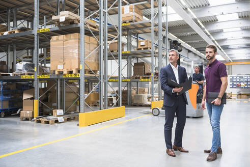 Two men and worker on forklift in high rack warehouse - DIGF10591