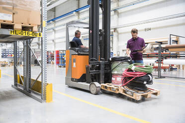 Warehouseman and worker on forklift in high rack warehouse - DIGF10598