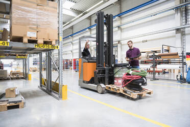 Warehouseman and worker on forklift in high rack warehouse - DIGF10599