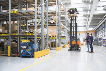 Two men and worker on forklift in high rack warehouse - DIGF10603