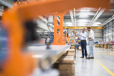 Zwei Männer unterhalten sich in einer Fabrikhalle - DIGF10610