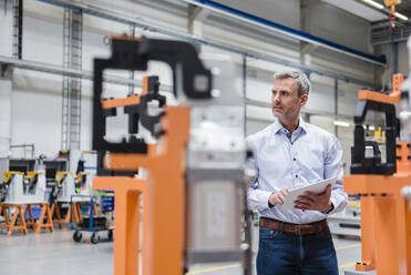 Mature man using tablet on factory shop floor - DIGF10615